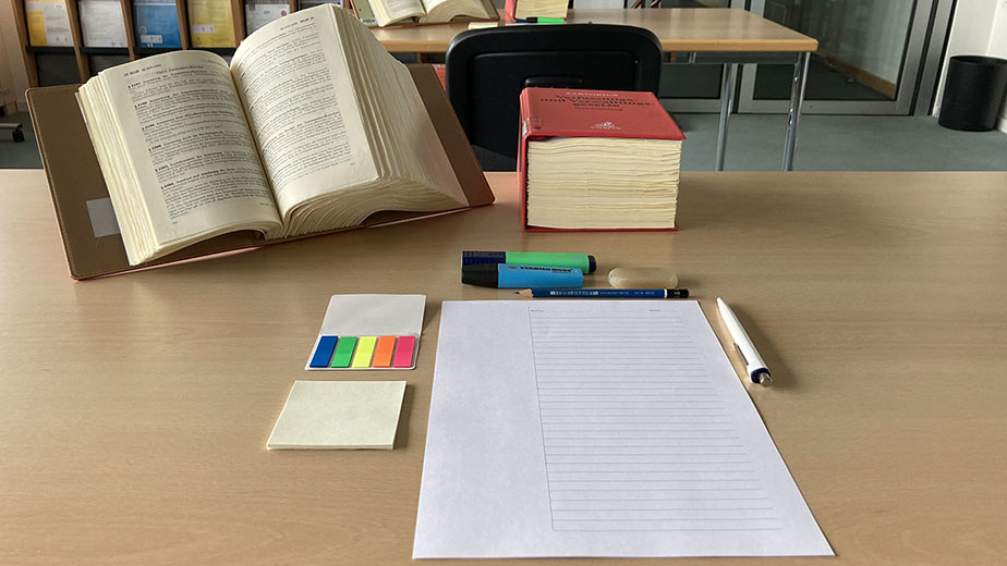 Abbildung von Gesetzestexten auf einem Tisch mit Papier und Schreibutensilien. (Quelle: Bundesamt für Justiz) Abbildung von Gesetzestexten auf einem Tisch mit Papier und Schreibutensilien.